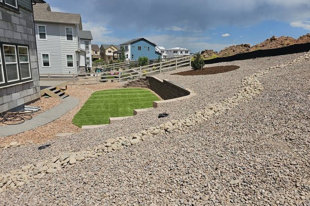Rock dry-creek drainage running beside a block retaining wall in Colorado Springs