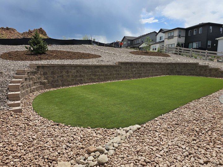 Block retaining wall with a rock drainage border, built on proper base to hold a slope