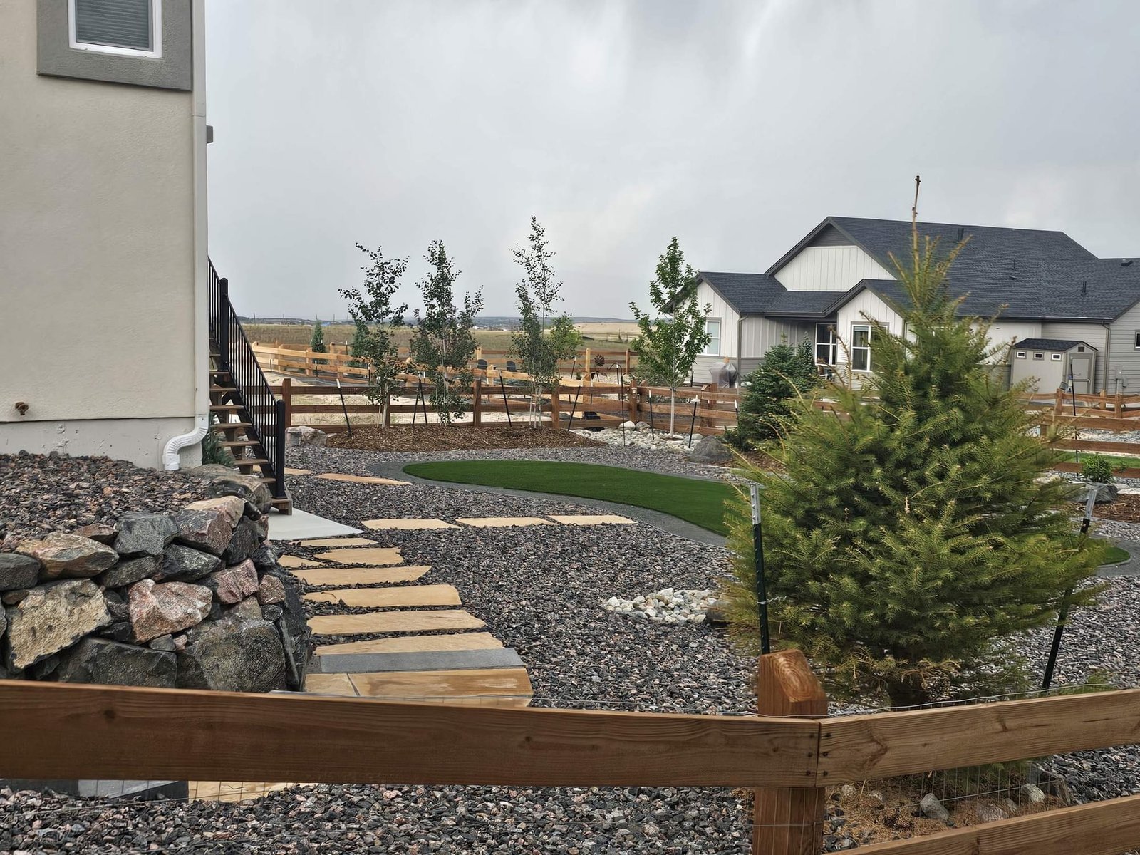 Finished backyard with artificial turf, boulders, and decorative gravel in Colorado Springs