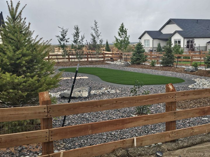 Artificial turf lawn framed by decorative rock and boulders, green all year on almost no water