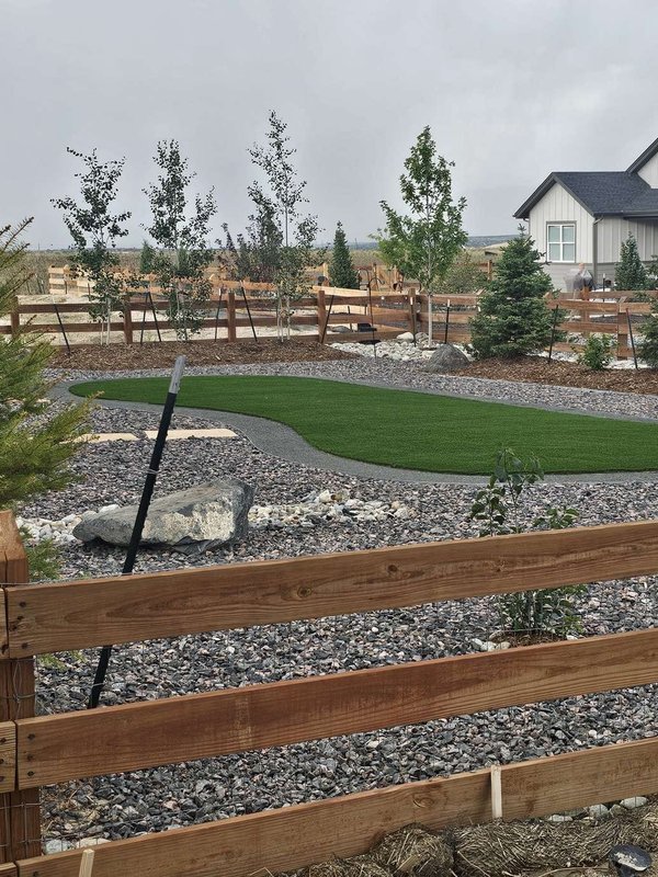 Kidney-shaped artificial turf lawn with decorative rock and boulders in Colorado Springs