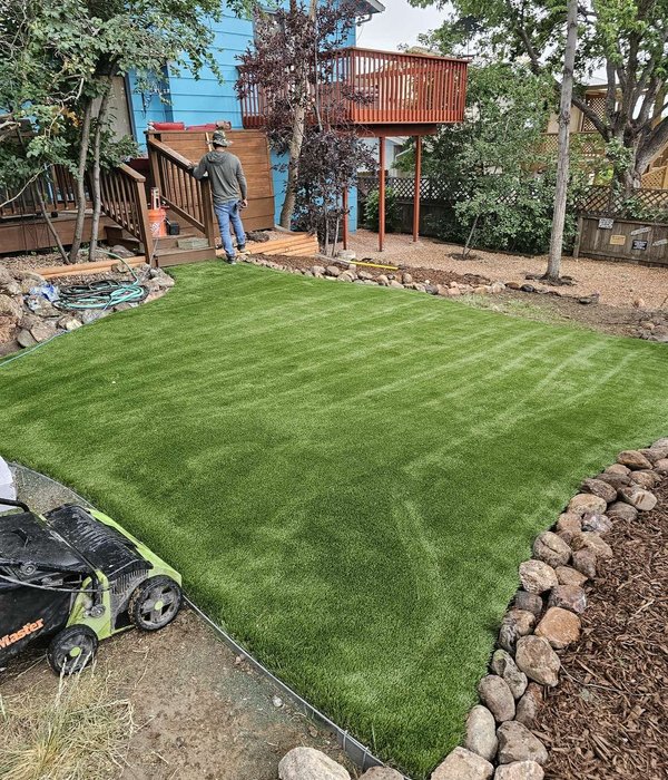 M&J Landscaping crew installing a new artificial turf lawn in a Colorado Springs backyard
