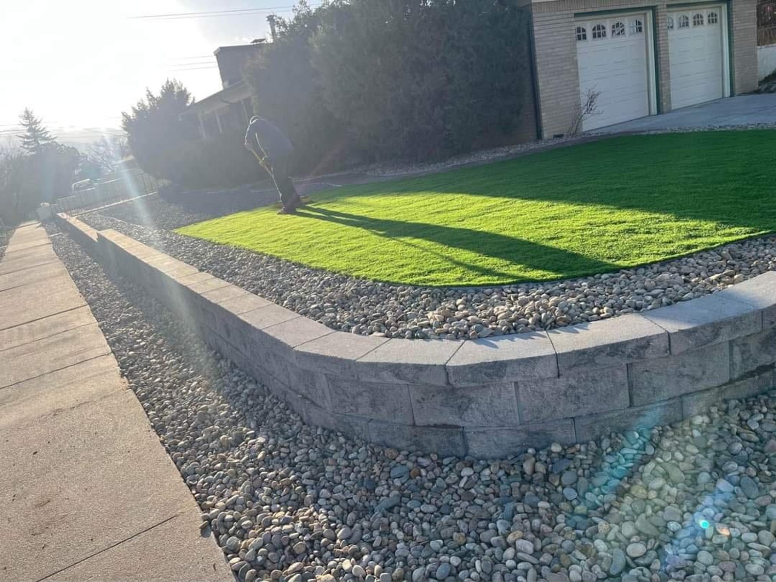 Block retaining wall holding a raised lawn with a clean rock border in Colorado Springs