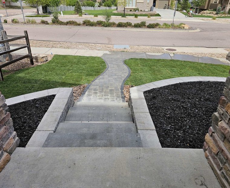 Finished hardscape with paver steps, stone pillars, and fresh sod in Colorado Springs